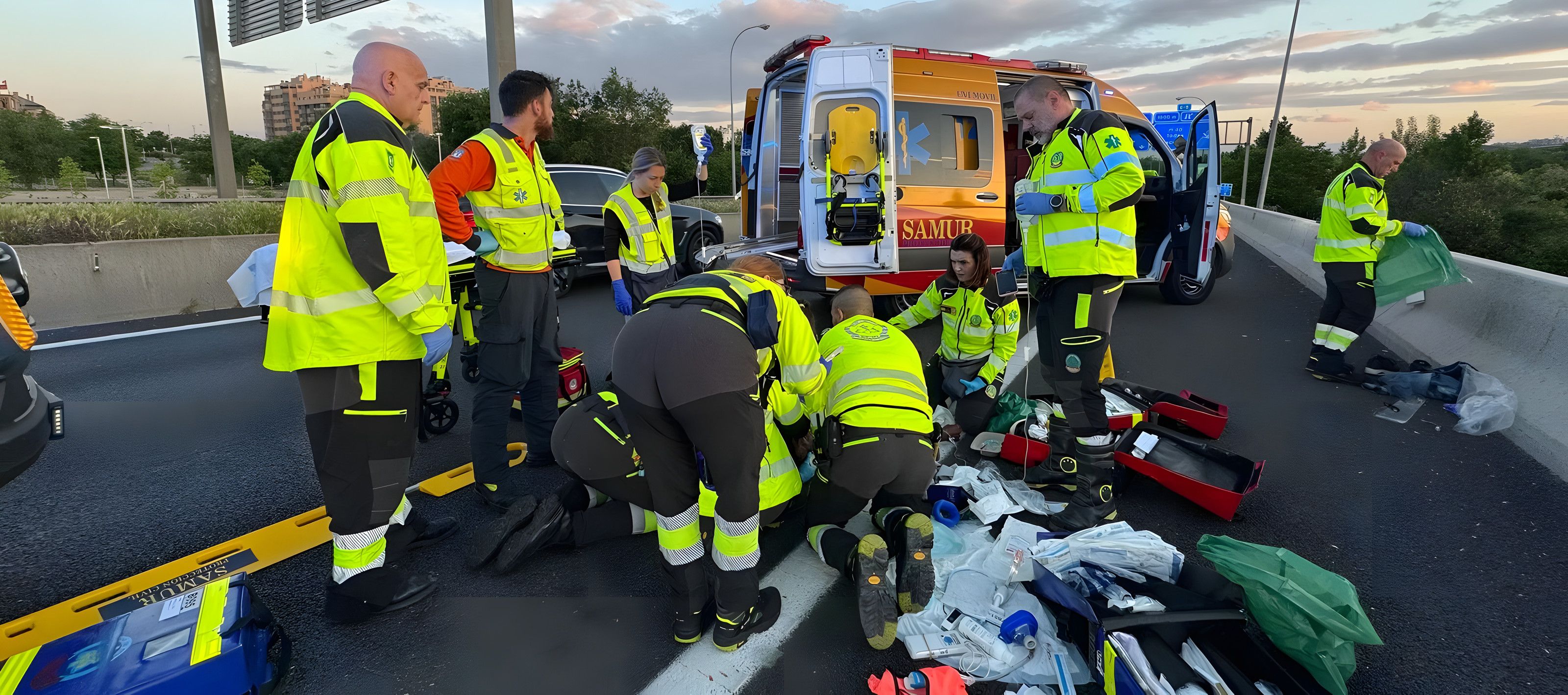 Equipo de SAMUR-Protección Civil atendiendo a un paciente en carretera junto a la ambulancia